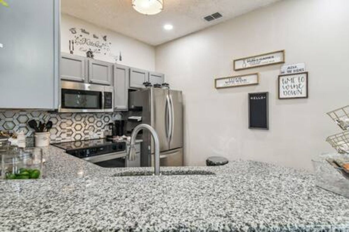 Una cocina moderna con encimeras de granito, electrodomésticos de acero inoxidable y decoración mural.