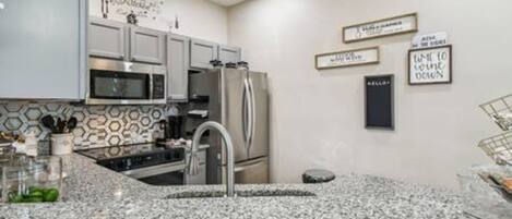 Una cocina moderna con encimeras de granito, electrodomésticos de acero inoxidable y decoración mural.