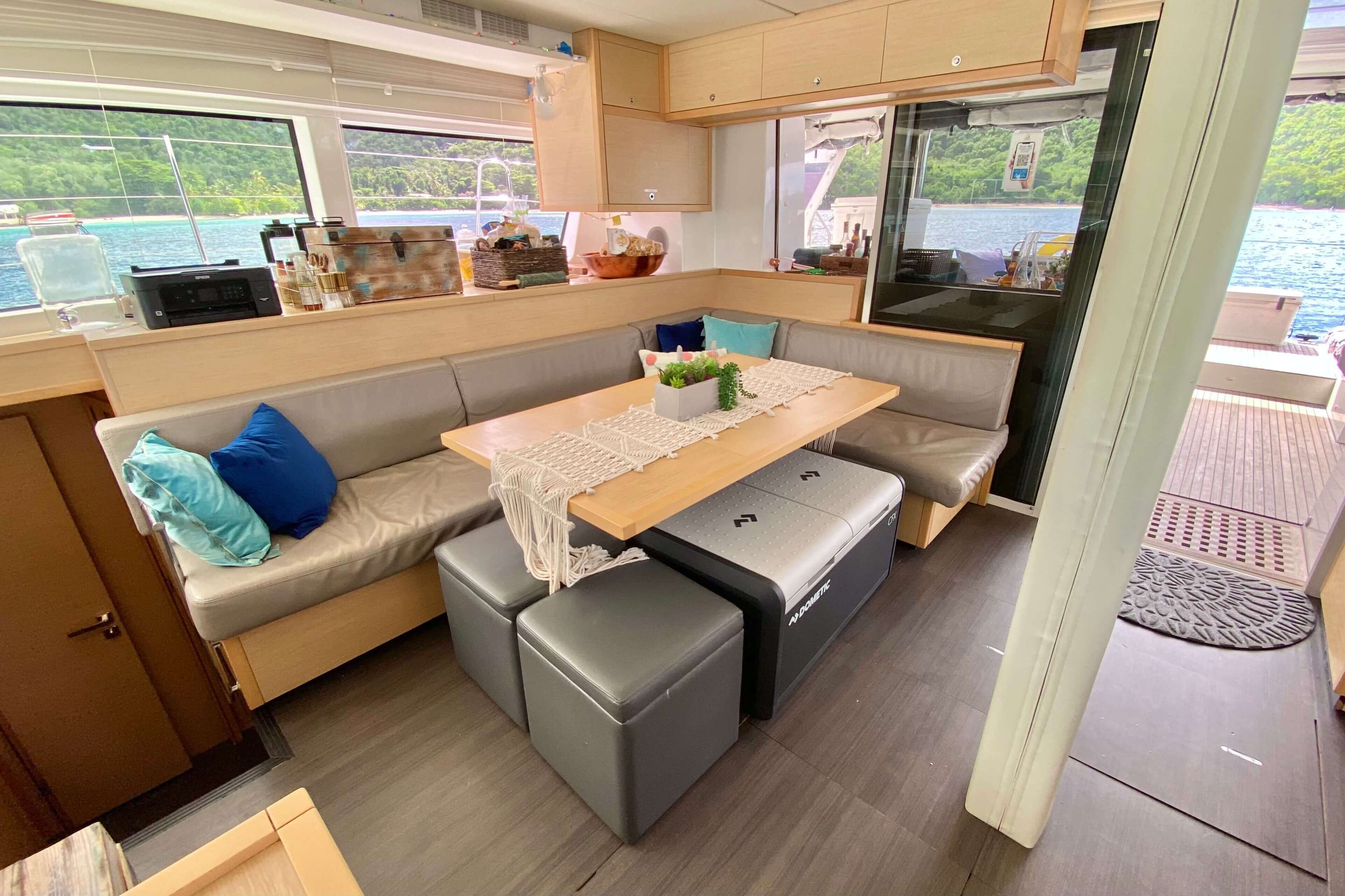 A compact galley with a central table, seating, and a view of the sea.
