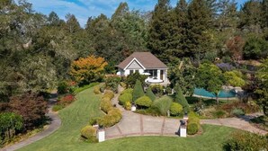 A house with a well-maintained lawn, a swimming pool, and a variety of trees and shrubs.
