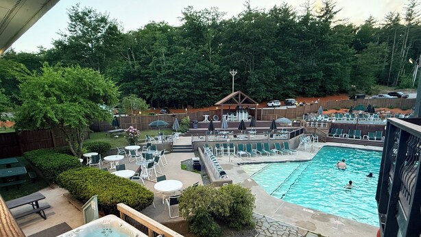 A pool area with lounge chairs, a hot tub, and a wooden deck. - Waterville Estate chalet perfect for relaxing stays Access to Pool, Hot Tub, Gym (Campton)