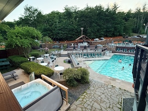 Een zwembadgedeelte met ligbedden, een jacuzzi en een houten terras.