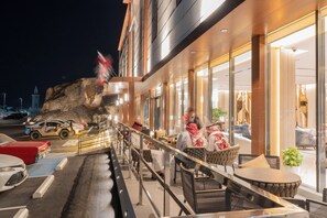 Et hotels ydre i nattens muld med moderne design, en balkon med siddepladser og udsigt til et klippefyldt landskab.