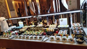 Un bufé con diversos platos y utensilios, como fuentes, platos y vasos.