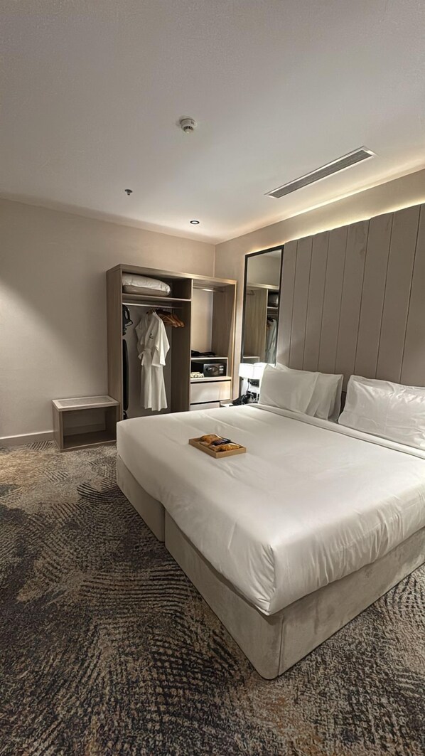Et moderne hotelværelse med en stor seng, et walk-in closet, et sengebord og et spejl.