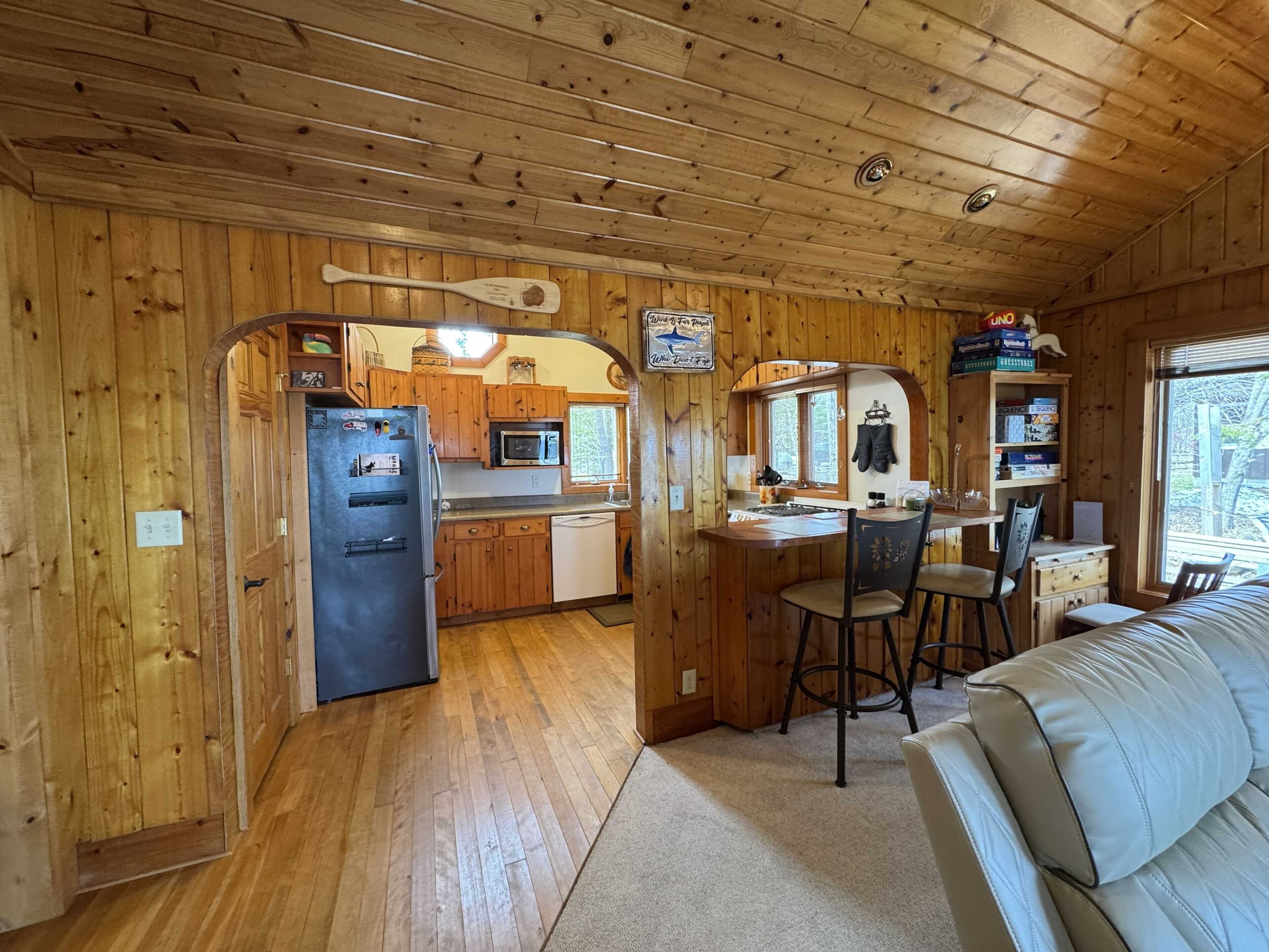 L’intérieur d’une cabane en bois comprend une cuisine, un coin repas et un salon avec un canapé.