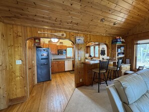 Ein Holzblockhaus-Innenraum mit Küche, Essbereich und Wohnzimmer mit einer Couch.
