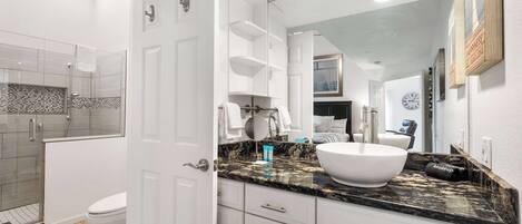 A modern bathroom with a white toilet, a glass-enclosed shower, and a large mirror above the sink.