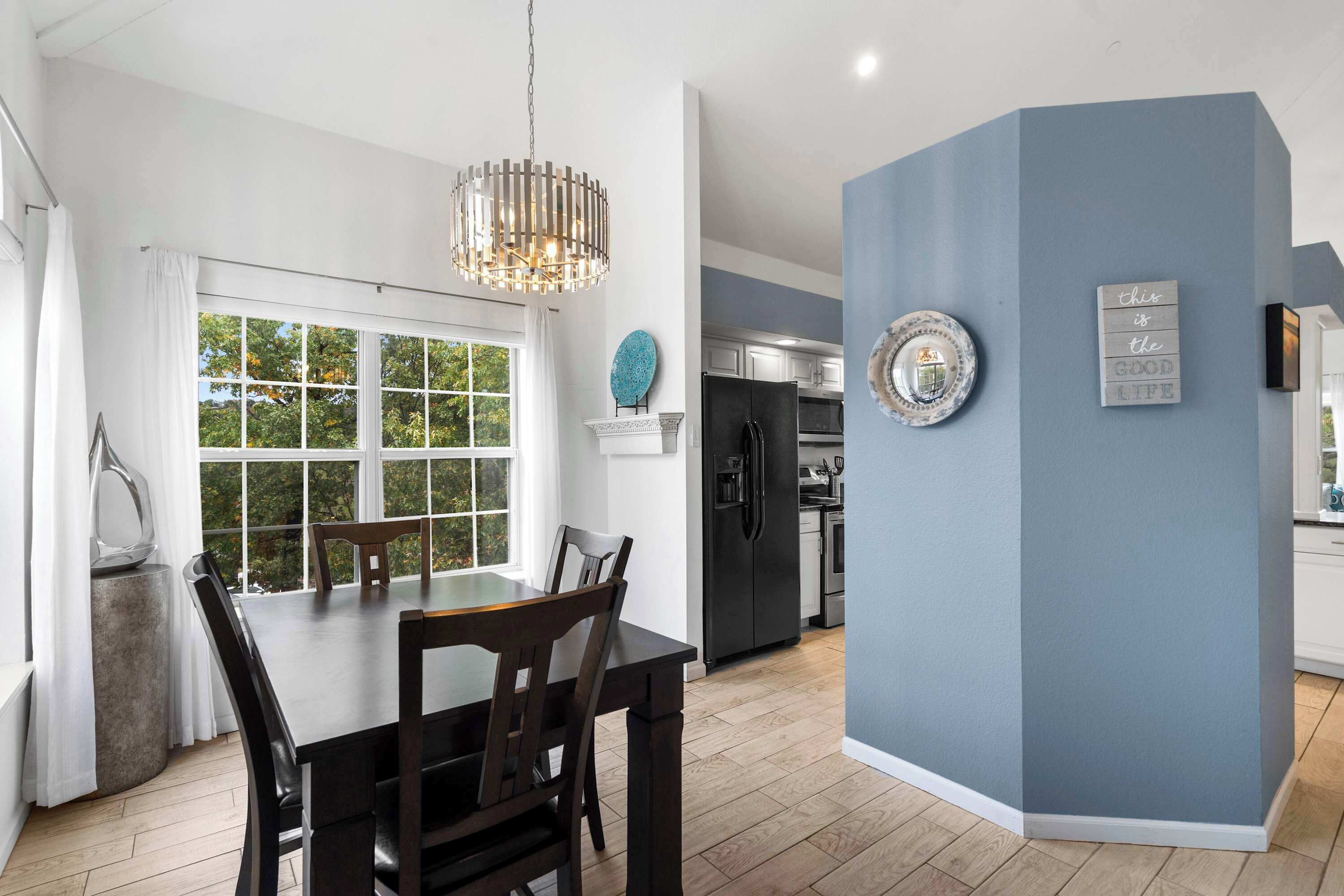 A modern kitchen with a black refrigerator, white cabinets, and a blue accent wall.