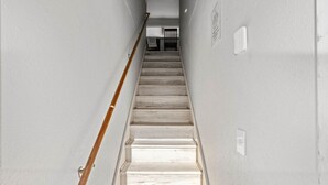 Eine schmale Treppe mit hölzernen Geländern und einer hellen Wand.