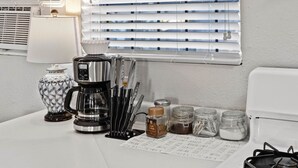 Eine Küche mit Kaffeemaschine, einer dekorativen Vase, einem Messerset und Gewürzgläsern auf der Arbeitsfläche.