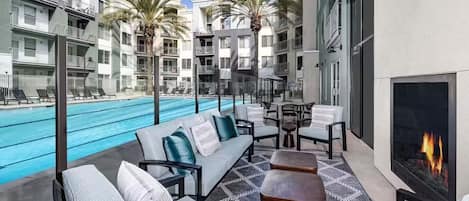 Un área de piscina en la azotea con asientos tipo lounge, una chimenea y vistas a la piscina.