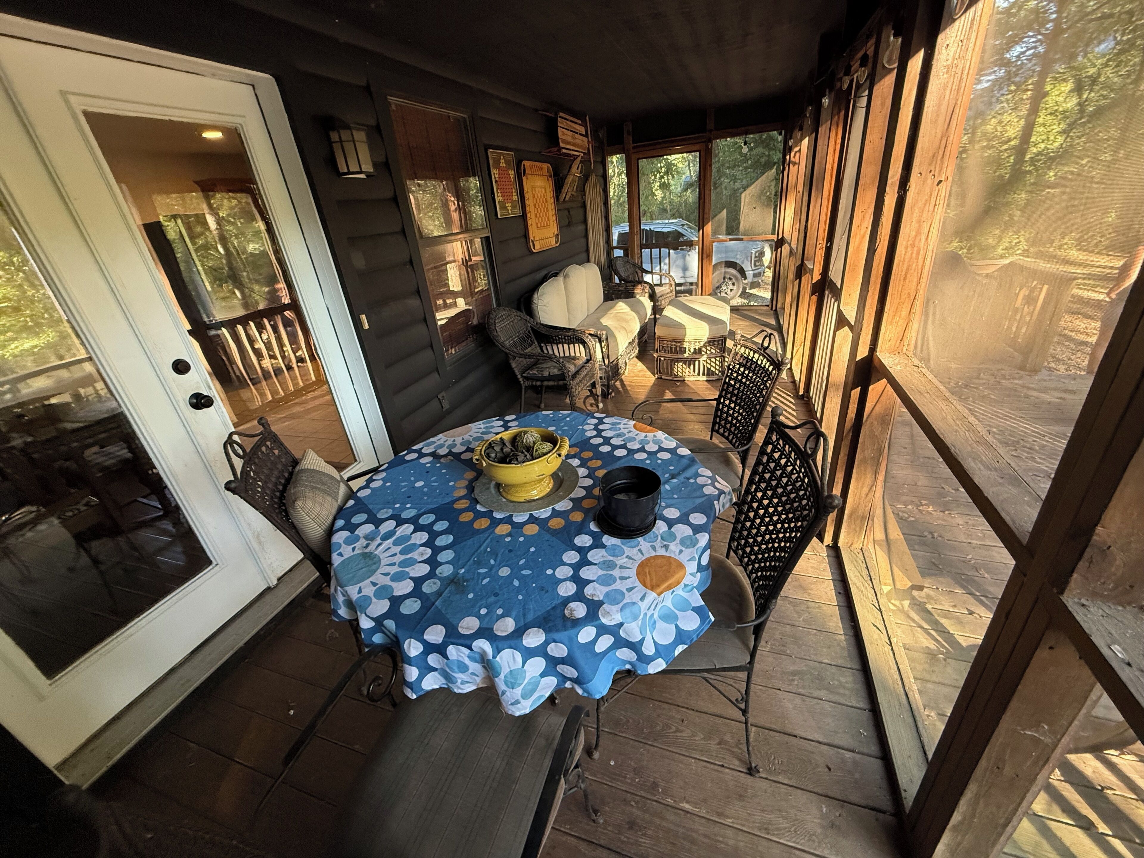 A covered outdoor patio with a round table, chairs, and a yellow bowl.