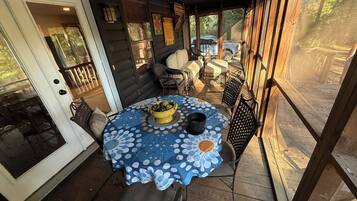 A covered outdoor patio with a round table, chairs, and a yellow bowl.