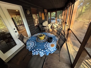 A covered outdoor patio with a round table, chairs, and a yellow bowl.