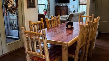 A dining area with a wooden table and chairs, a chandelier, and a ceiling fan.
