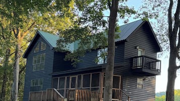 A two-story log cabin with a balcony and a large window.