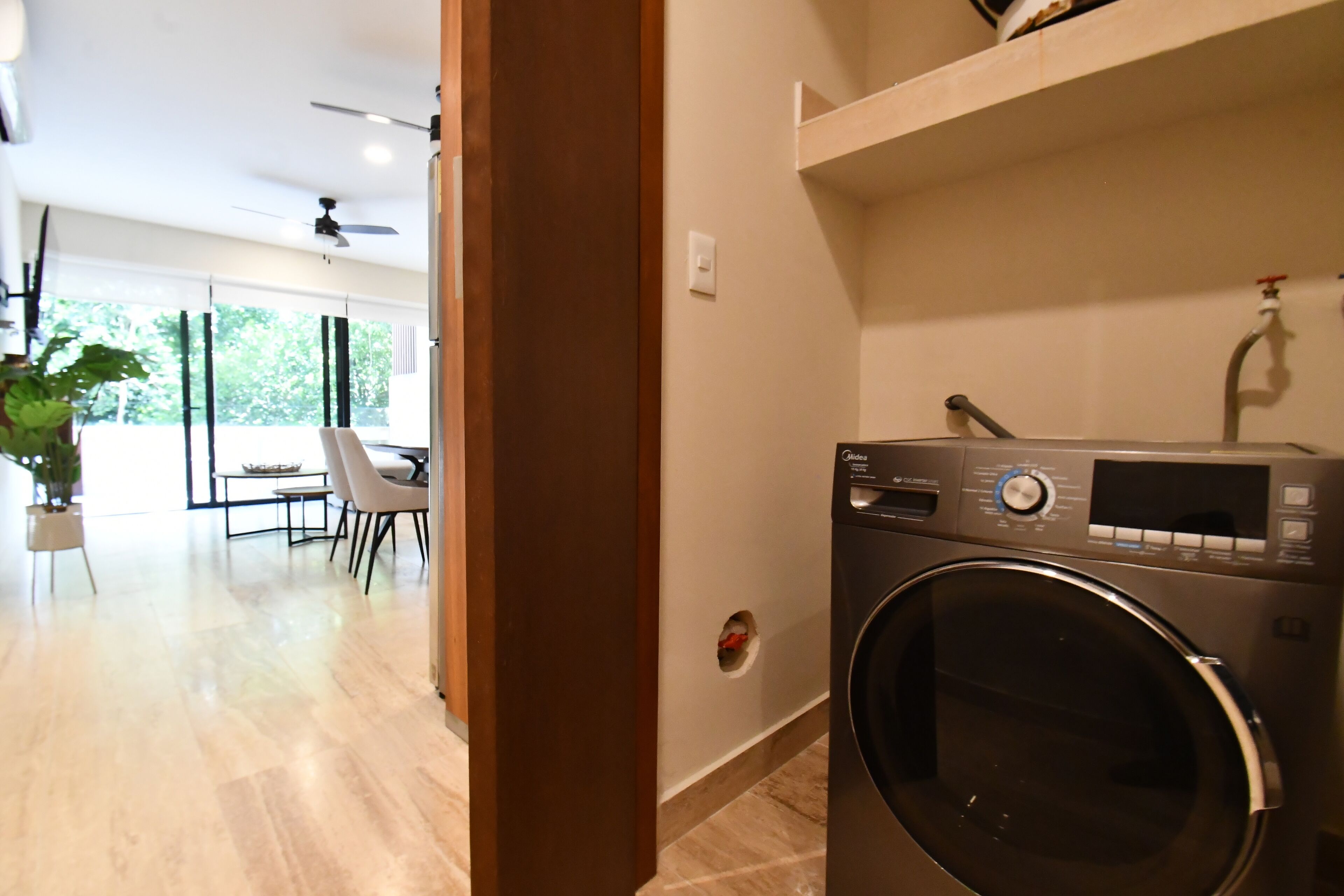 A laundry room with a front-loading washing machine, a sink, and a ceiling fan.