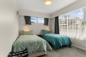 Una camera da letto con due letti, una finestra con tende e una lampada a soffitto.