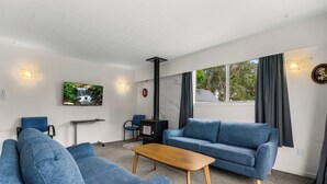 Ein modernes Wohnzimmer mit einem blauen Sofa, einem Holztisch und einem an der Wand montierten Fernseher.