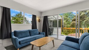 Ein modernes Wohnzimmer mit einem blauen Sofa, einem Holztisch und Blick auf einen Balkon mit Geländer.