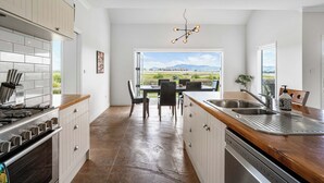 Una cucina moderna con isola centrale, zona pranzo con sedie e vista sull'esterno.