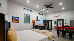 A modern hotel room with a bed, a dining table with chairs, a kitchenette, and a ceiling fan. - Double Magic - Unique Cabin for 6 - Pond, Hot Tub (Broken Bow)