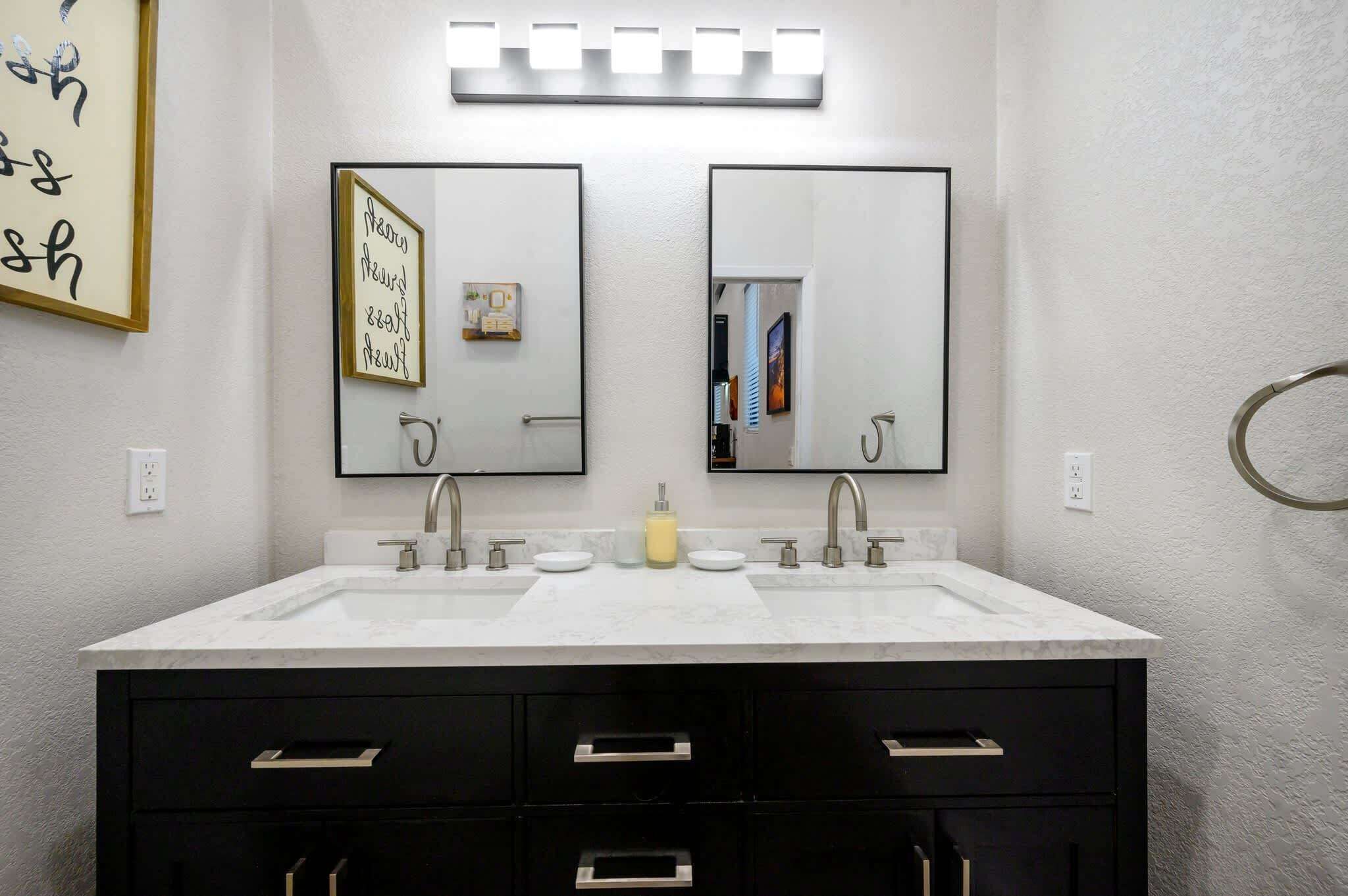 A bathroom with a white vanity, two mirrors, and a towel ring.