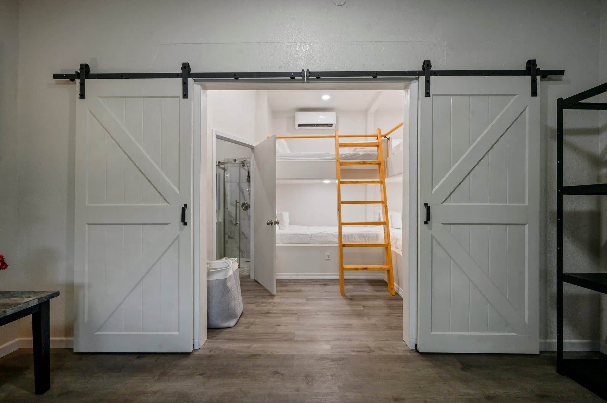 Une pièce avec un lit en mezzanine, une échelle en bois et une porte coulissante de style grange.