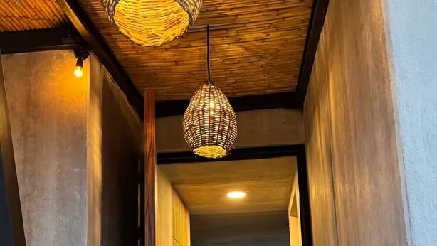 A modern interior with a wooden ceiling, a hallway leading to a living area with a sofa and large windows.