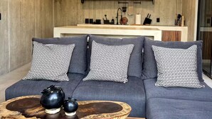 A modern living room with a grey sofa, black and white patterned cushions, a wooden coffee table, and a ceiling fan.