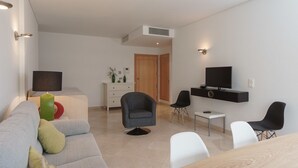 A modern living room with a sofa, chairs, a TV, and a small table. - Vilamourasun Aquamar 112 (Loulé)