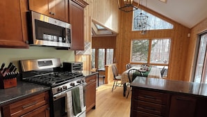 Una cocina moderna con armarios de madera, una estufa de acero inoxidable y un ventanal con vistas a un bosque.