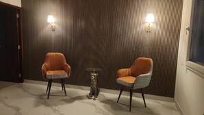 Een kamer met twee oranje fauteuils, een klein rond tafeltje en een luipaardbeeld.