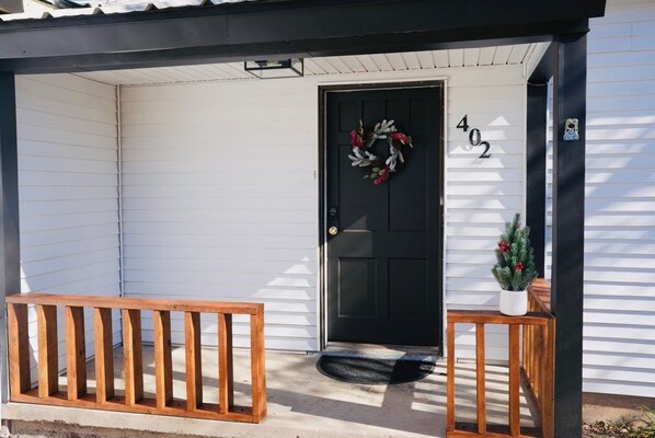 A house with a black front door, a wooden porch, and a mailbox.
