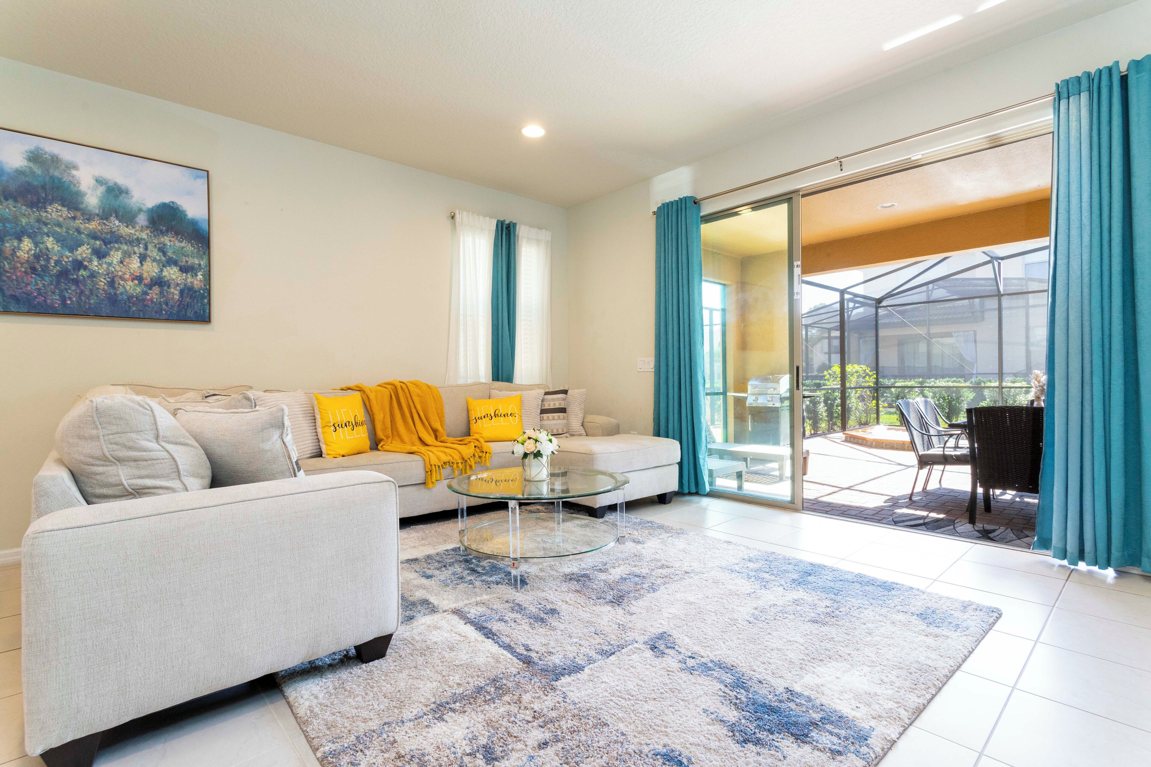 Een moderne woonkamer met een bank, een bijzettafeltje en een glazen deur die uitkomt op een terras.