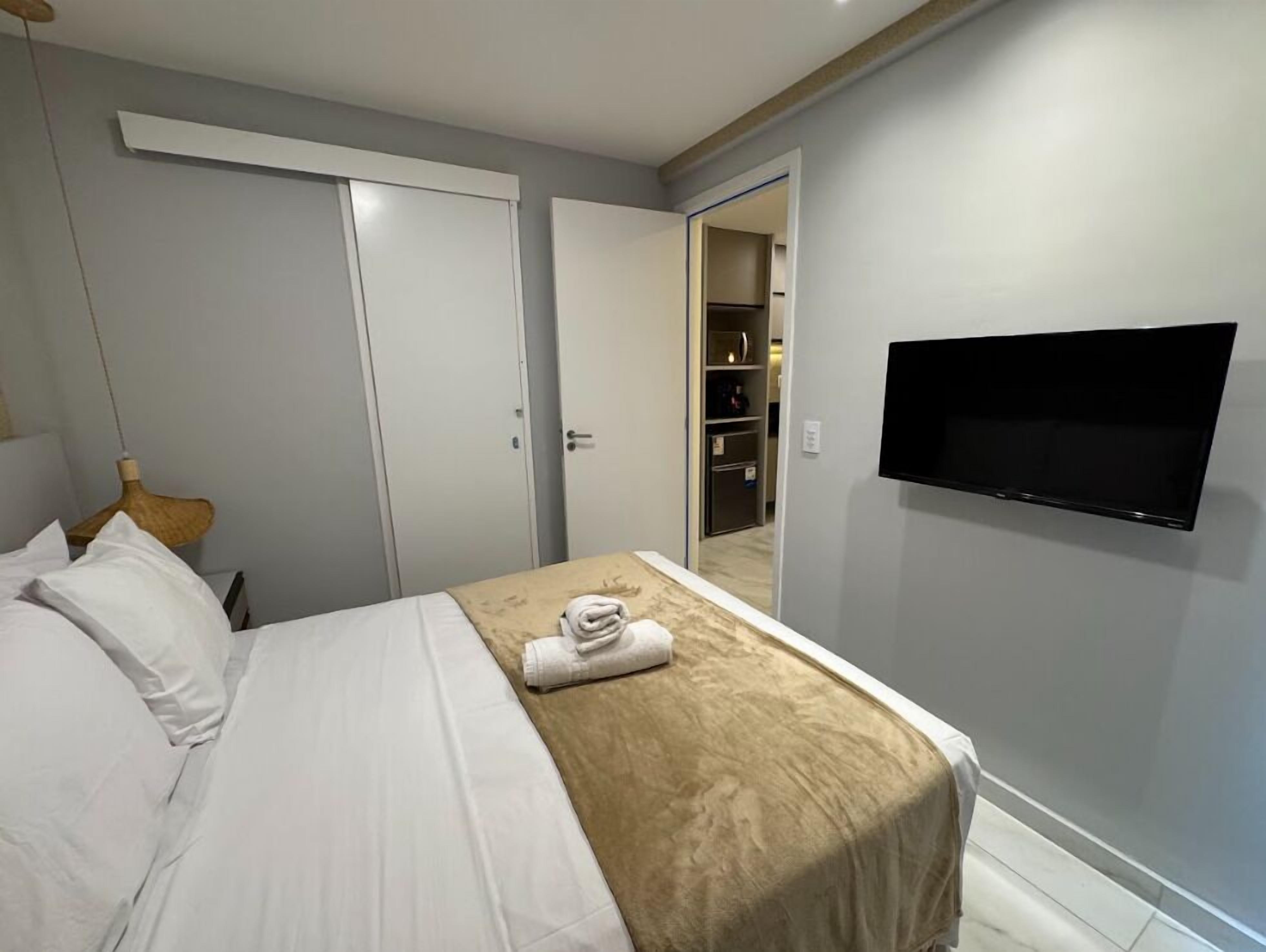 Une chambre d’hôtel avec un lit, un téléviseur fixé au mur et une armoire.