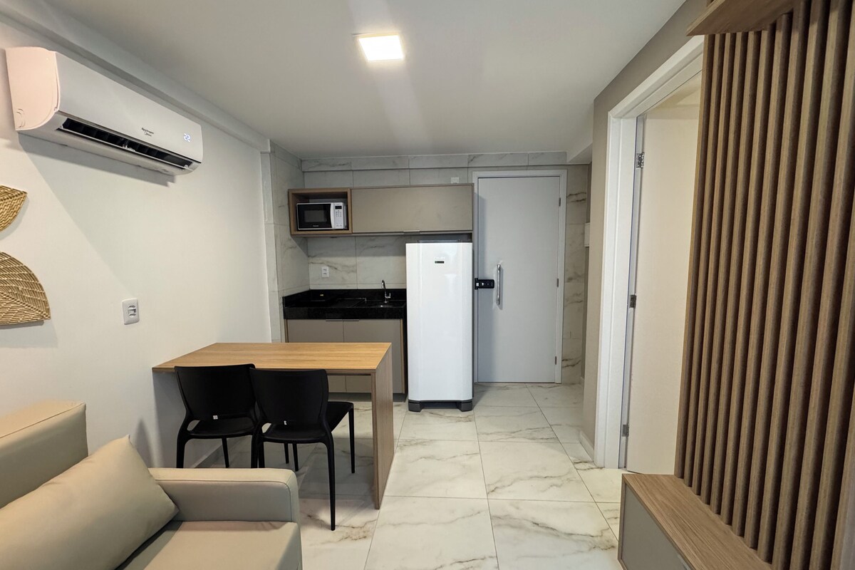 A compact kitchen with a microwave, refrigerator, and a dining area with a table and chairs.