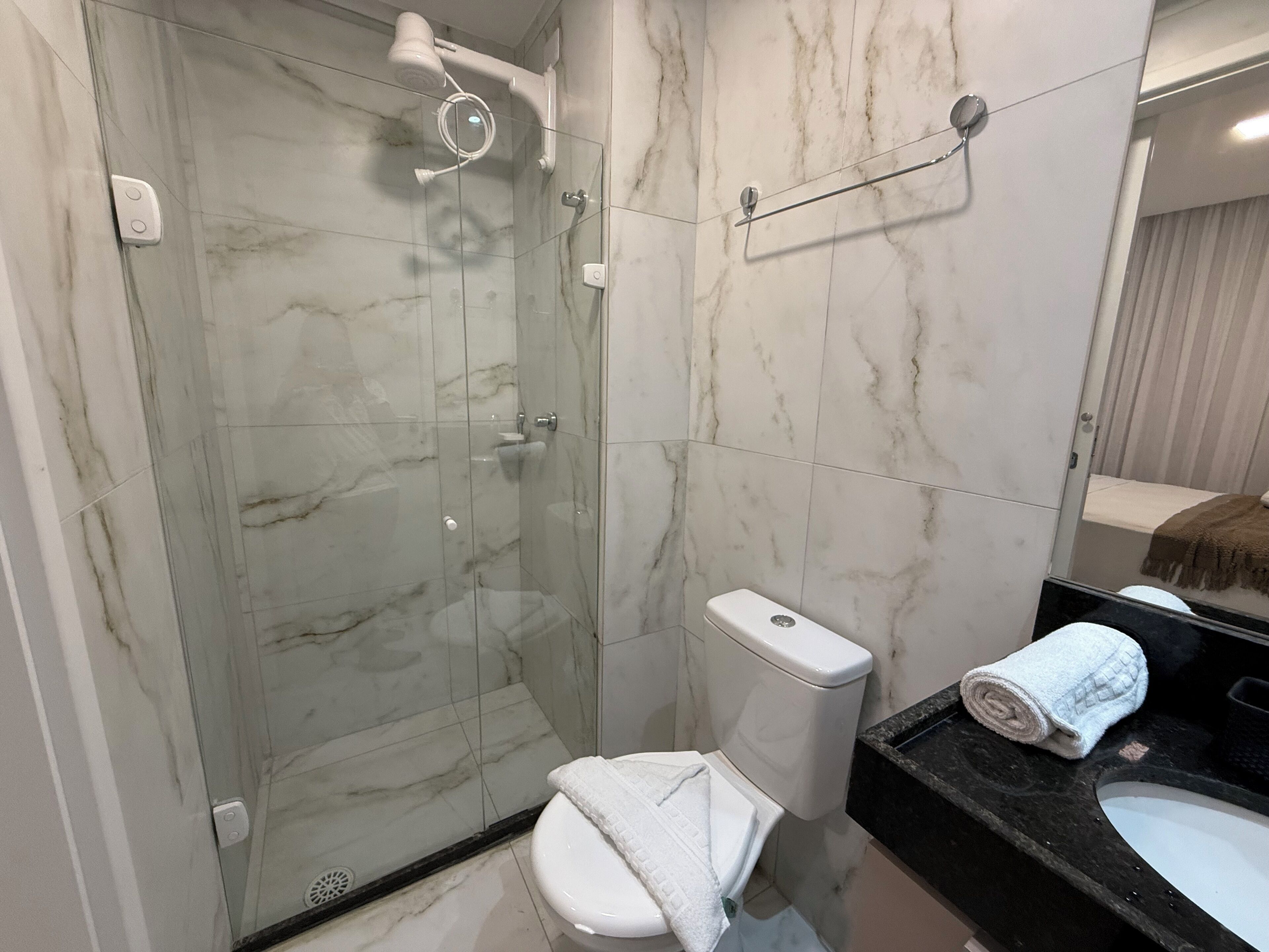 Ein modernes Badezimmer mit einer Duschkabine, einer Toilette und einem Waschbecken mit Handtuch.