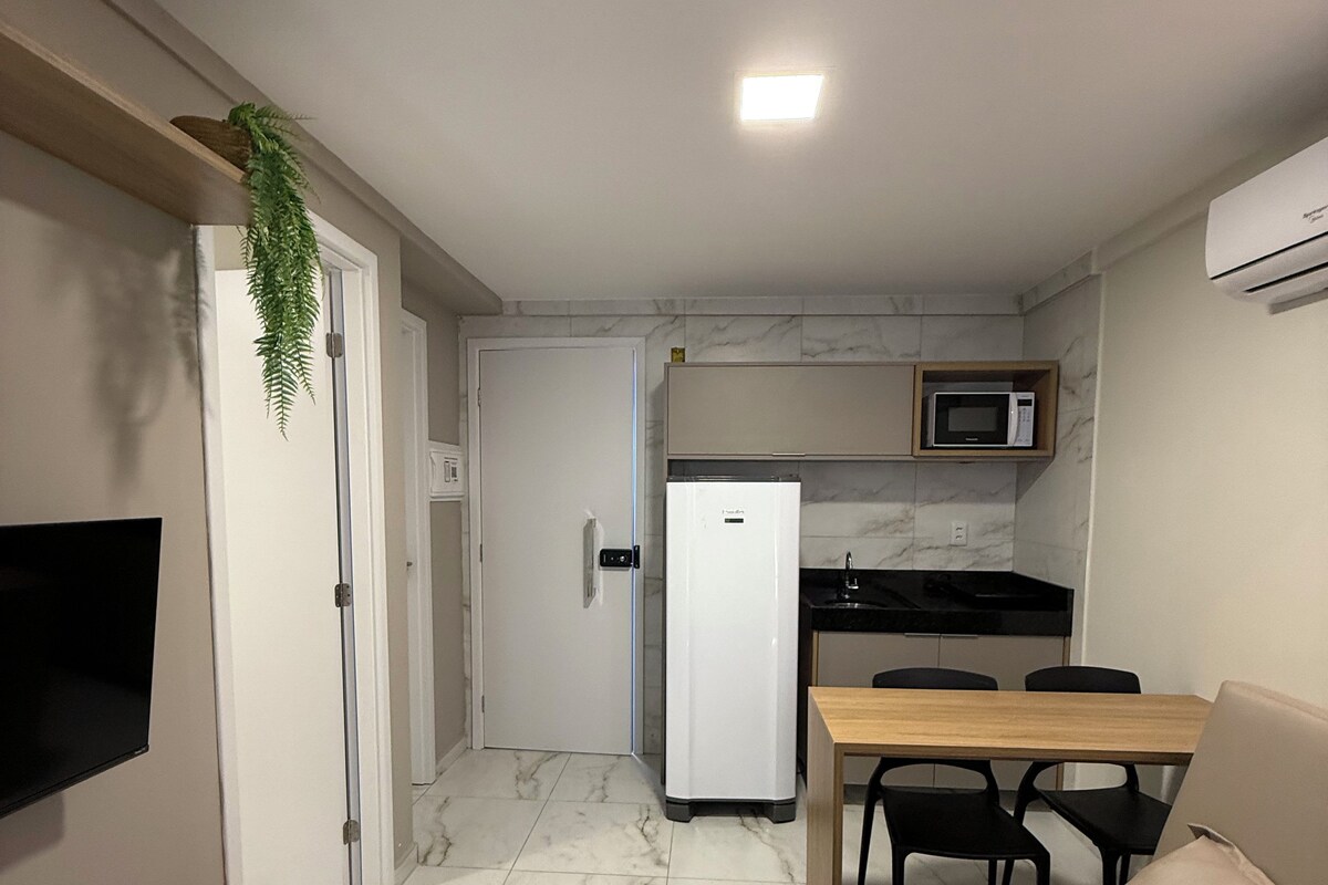 A compact kitchen with a refrigerator, microwave, and a dining area with a table and chairs.