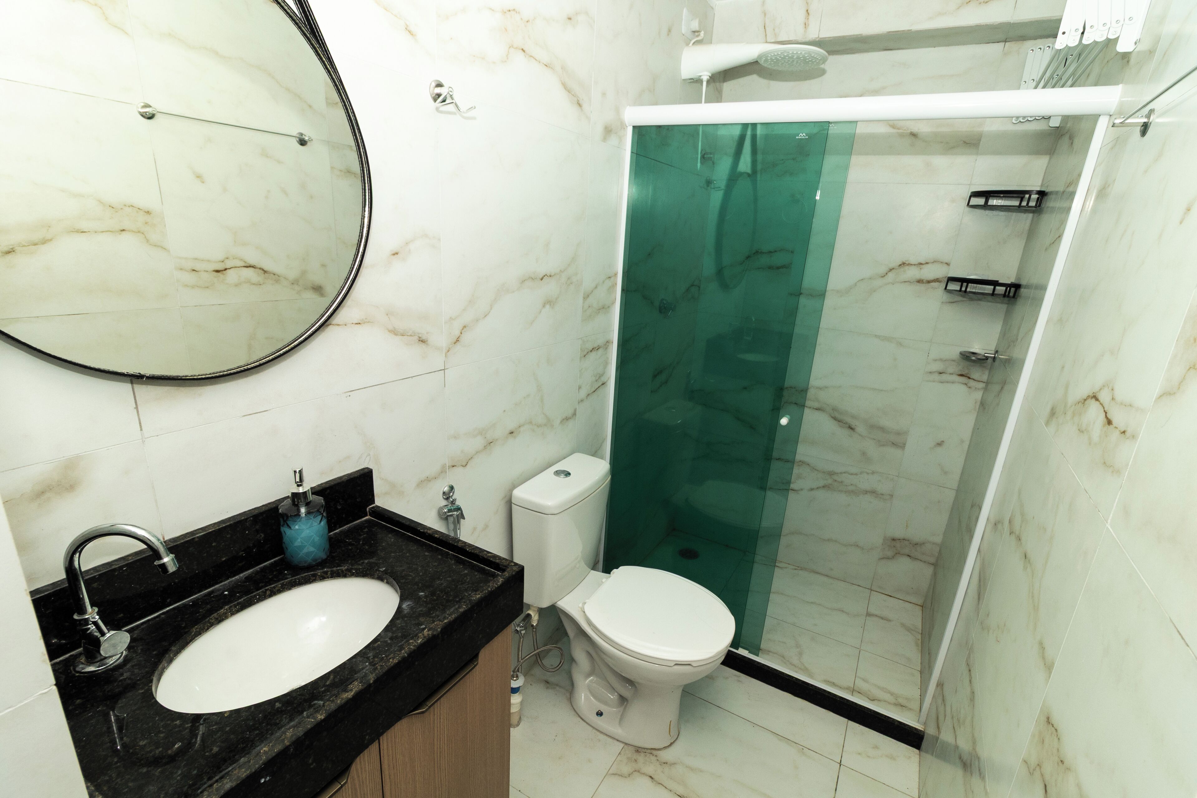 A bathroom with a marble sink, toilet, and a glass shower enclosure.