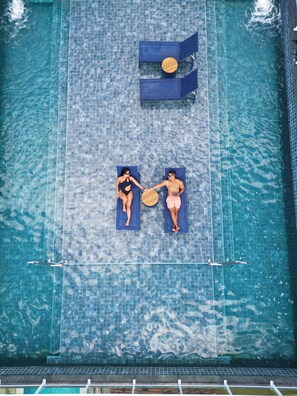 Vista aérea de una piscina con dos sillas de descanso y una tumbona.