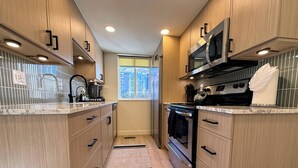 Een moderne keuken met houten kastjes, roestvrijstalen apparatuur en een raam met uitzicht.
