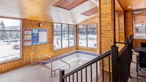 Ein Holzinnenraum mit Wellnessbereich, einschließlich Whirlpool und einem Schild mit Sicherheits- und Spa-Regeln.