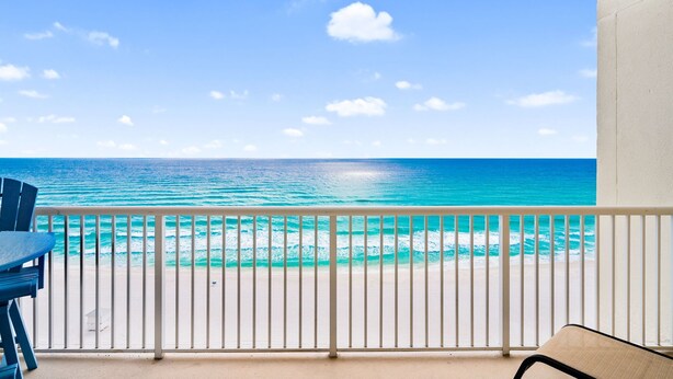 A balcony with a view of the ocean, a white railing, and a blue chair. - Majestic 1009 | Cozy Gulf-Front Studio + Free Fun! (Panama City Beach)