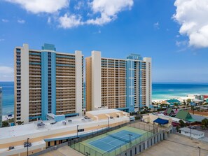 Un hotel alt amb nombroses plantes, una pista de tennis a la teulada i vistes a l'oceà i la platja.