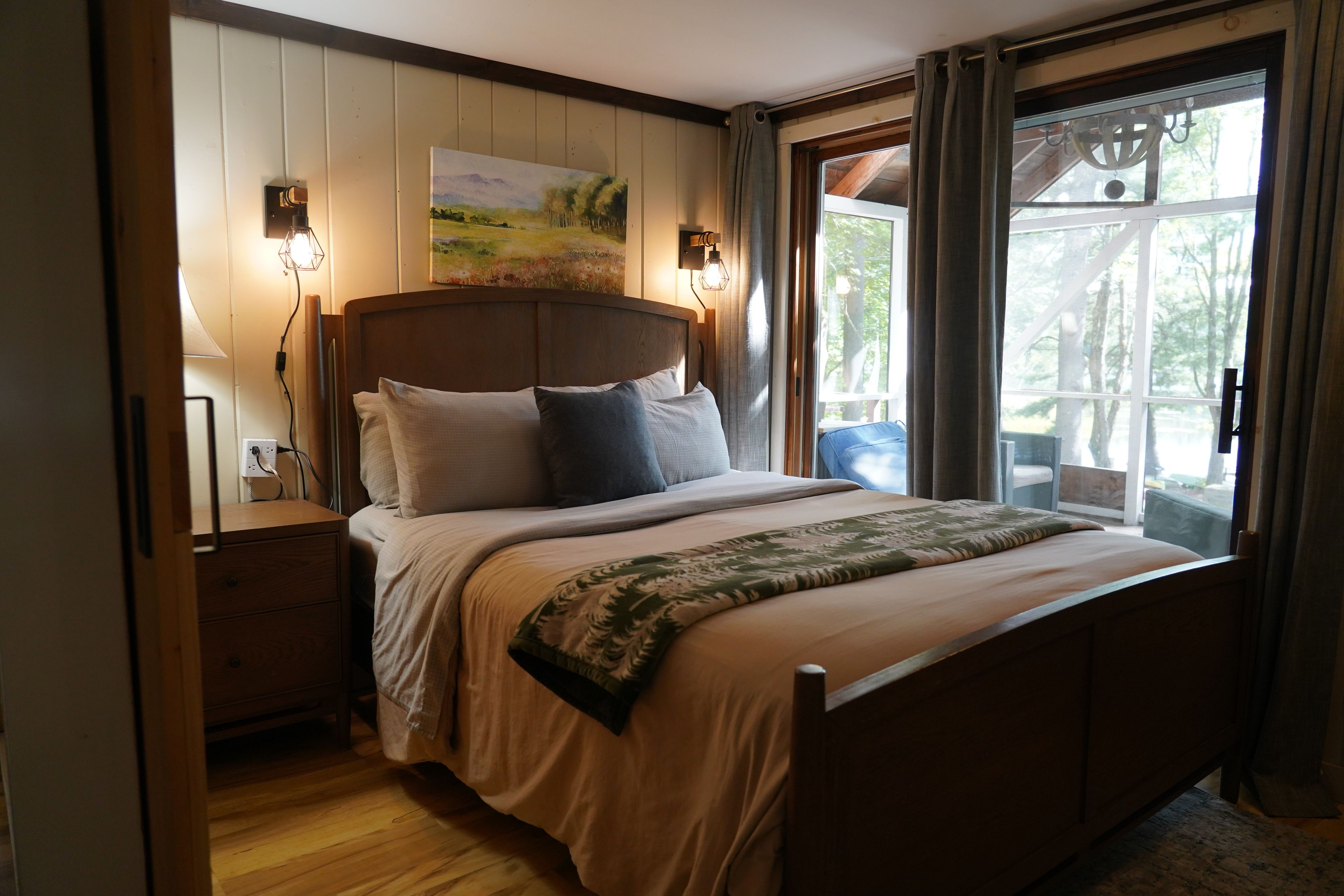 A bedroom with a wooden bed, a nightstand, a lamp, and a painting on the wall.