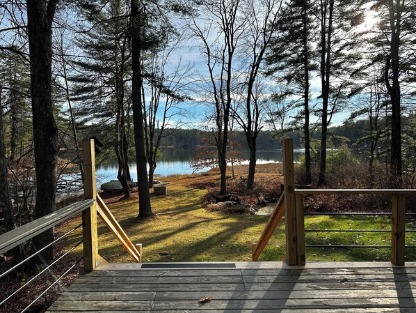 A wooden deck leading to a lake surrounded by trees. - Peaceful Family Friendly Private Lake Waterfront Home Close to Skiing and Hiking (Bennington)