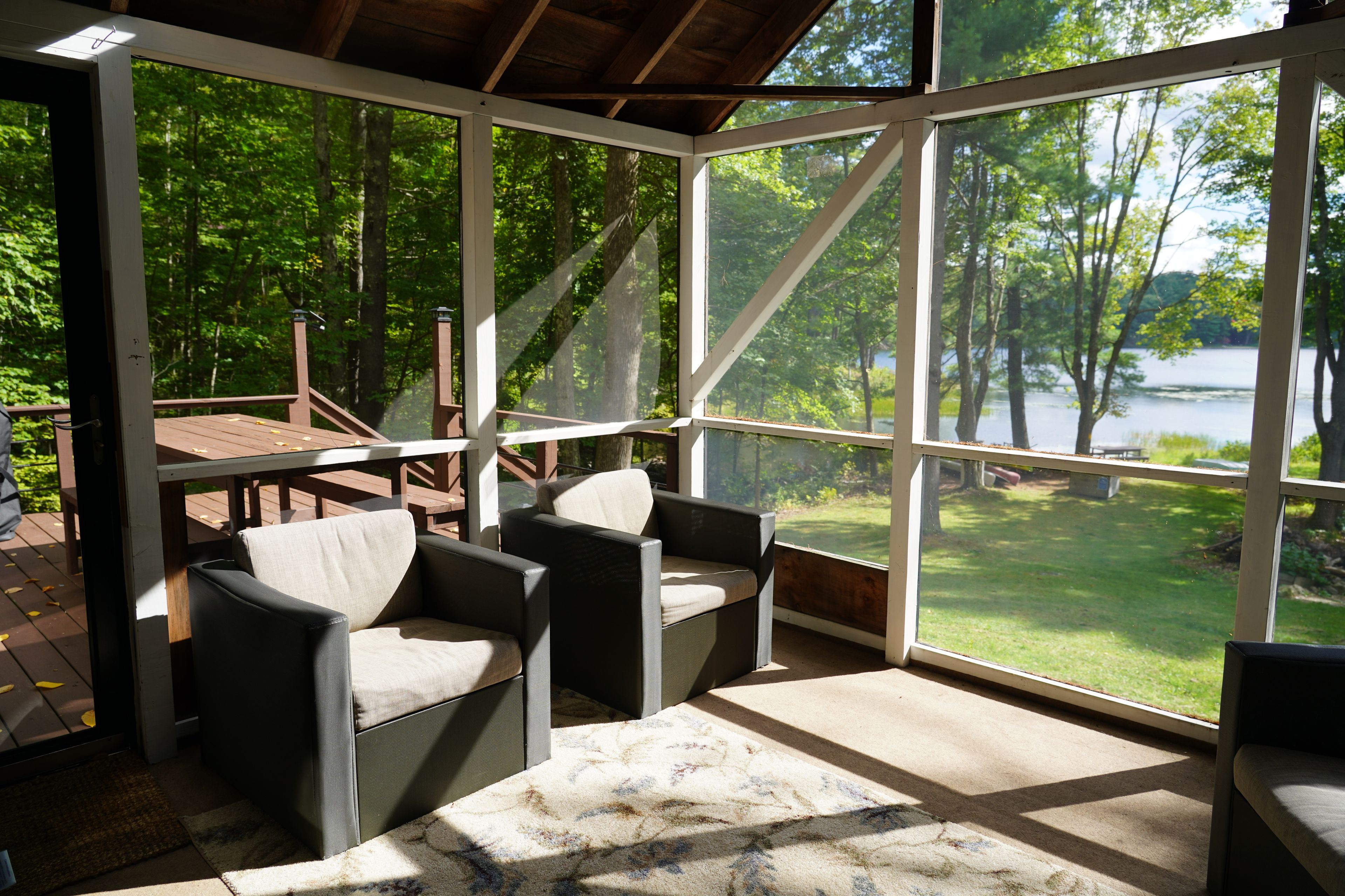 A covered outdoor seating area with a view of a lake and trees.