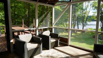 A covered outdoor seating area with a view of a lake and trees.